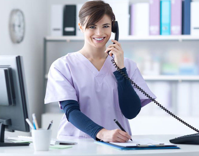 Medical receptionist in the process of booking a patient appointment over the phone.